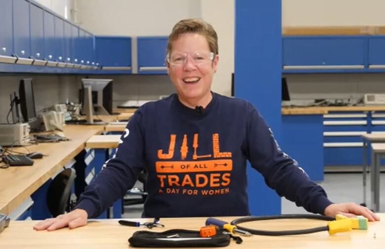 Woman wearing safety goggles stands in front of table with tools.