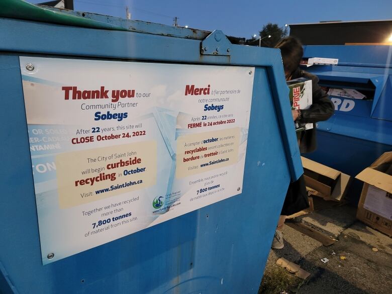 A sign posted on the side of a large recycling bin reads: 