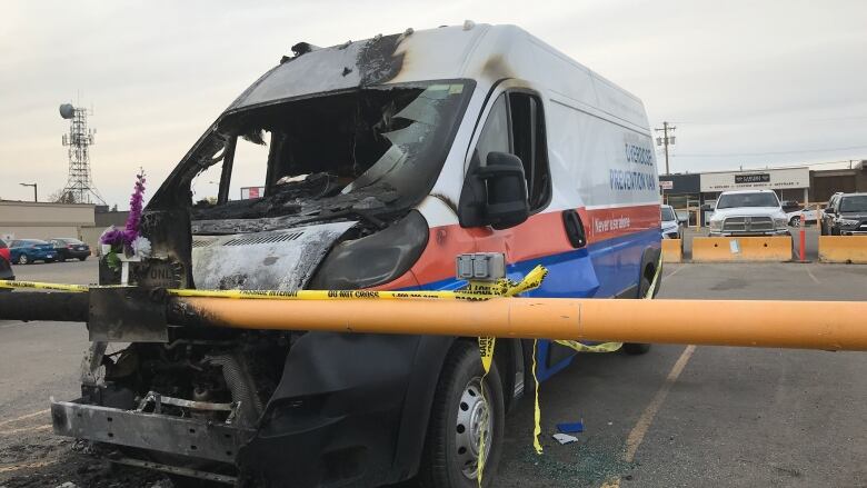 A gutted vehicle is seen behind yellow crime tape.