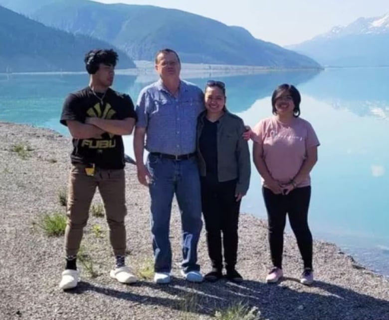 A family poses in front of a lake.