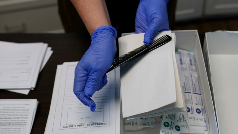 A top view of a person wearing medical gloves unpacking swabs and a comb.