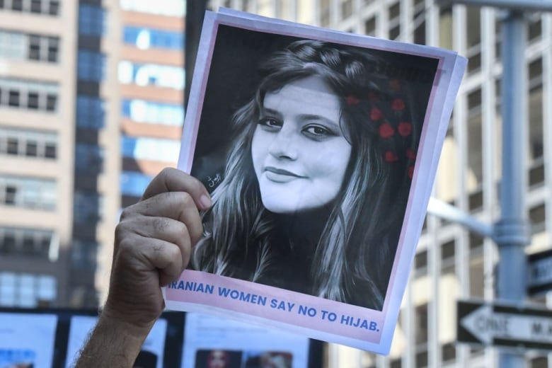 An arm holds up a photo of an Iranian woman in a protest against Iranian President Ebrahim Raisi outside of the United Nations.