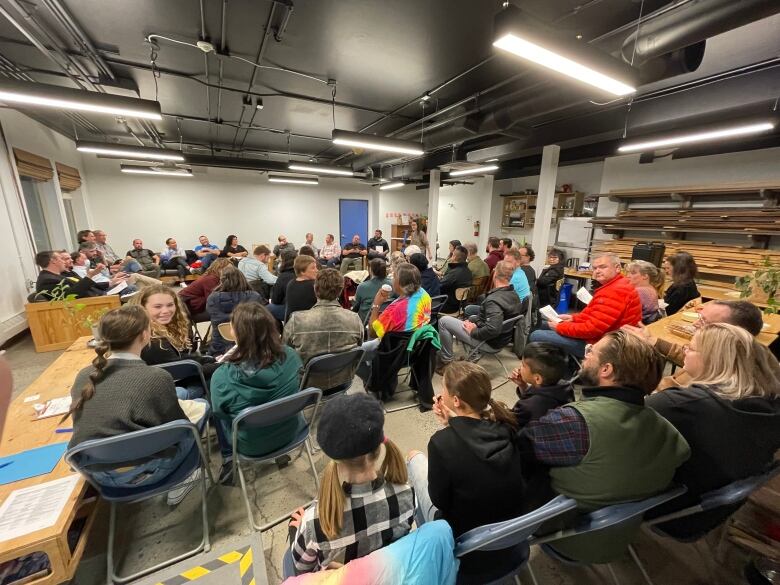 Crowded room, people on folding chairs. 