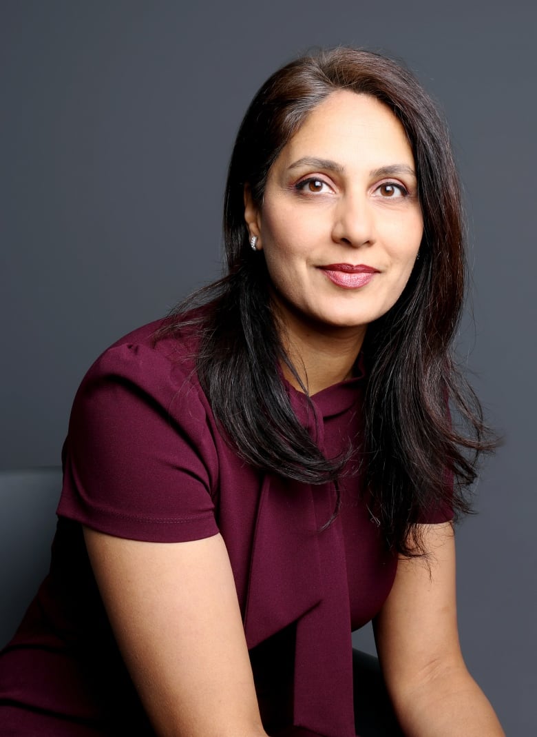 A woman with a slight smile, wearing a burgundy blouse, poses for a portrait. 