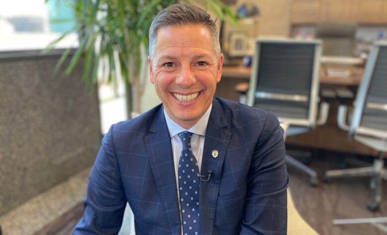 Man in blue suit with big smile looking at camera.