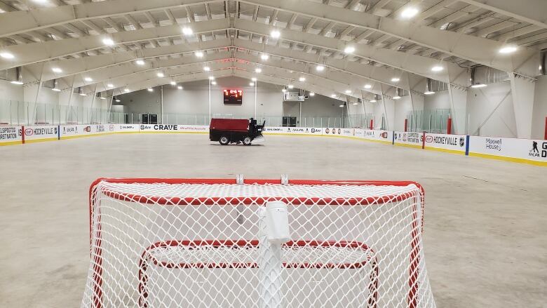 The interior of a hockey arena with hockey nets in the foreground and a Zamboni in the background.