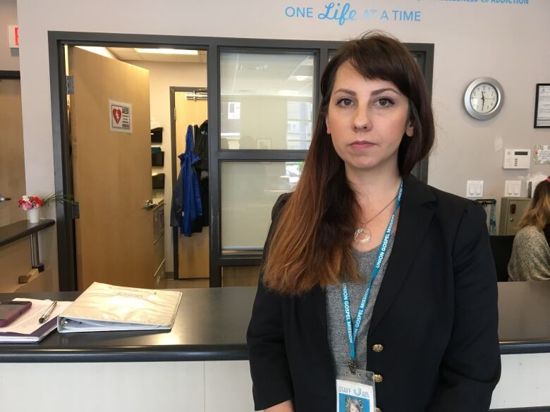 A brunette woman stands in front of a counter.