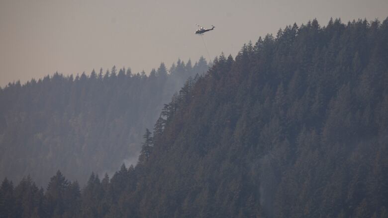 helicopter flies over Minnekhada Regional Park during a wildfire