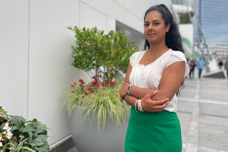 A brown woman stands next to a planter.