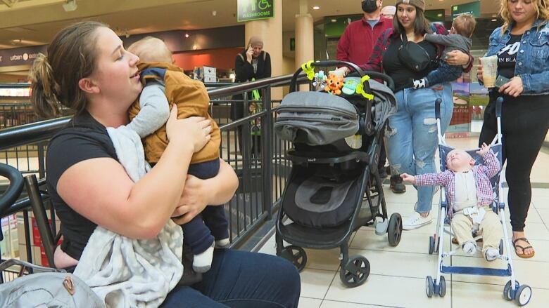 Parents hold their kids while lined up for relief payments