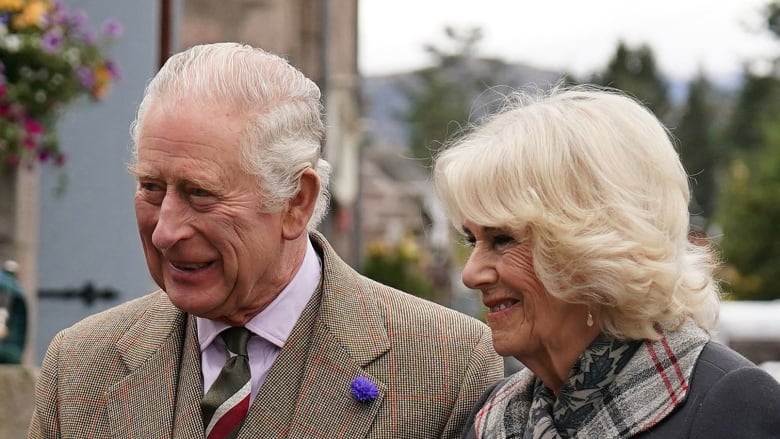 A grey haired man and blond woman standing side by side smiling