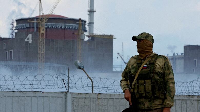 A Russian soldier with a rifle stands near the Zaporizhzhia Nuclear Power Plant in Ukraine.