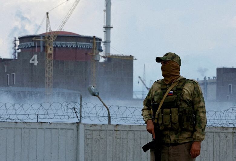 A Russian soldier with a rifle stands near the Zaporizhzhia Nuclear Power Plant in Ukraine.