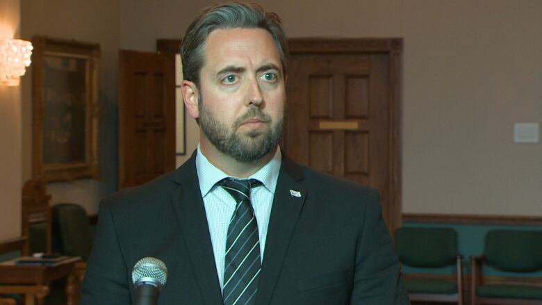 A man wearing a suit stands in the media scrum area of the Confederation Building in St. John's.