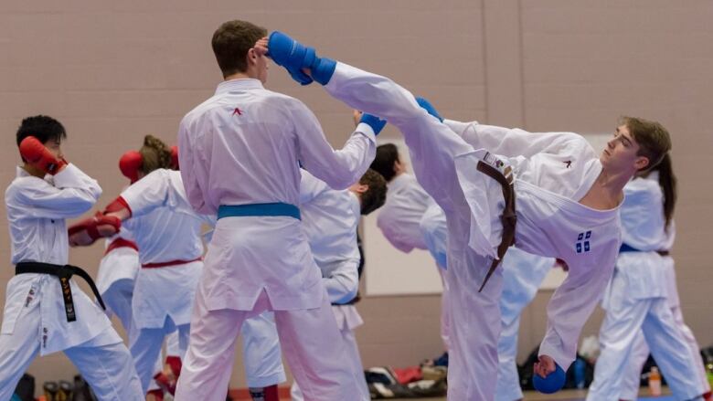 Two teenage boys are sparring. One boy's foot is near the other's head.