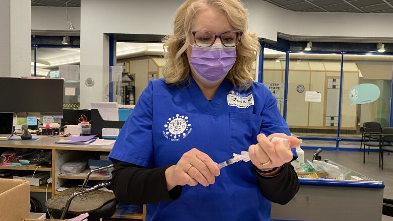 A nurse prepares a needle.