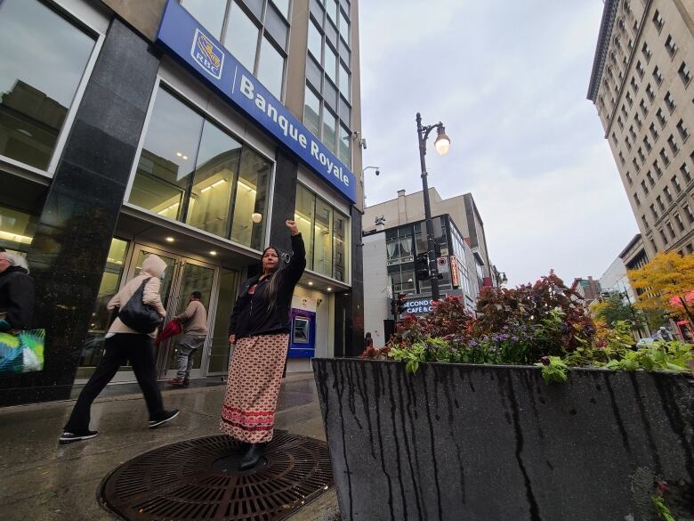 Chief Judy Wilson stands in the rain outside in downtown Montreal, raising her fist in front of an RBC branch. 