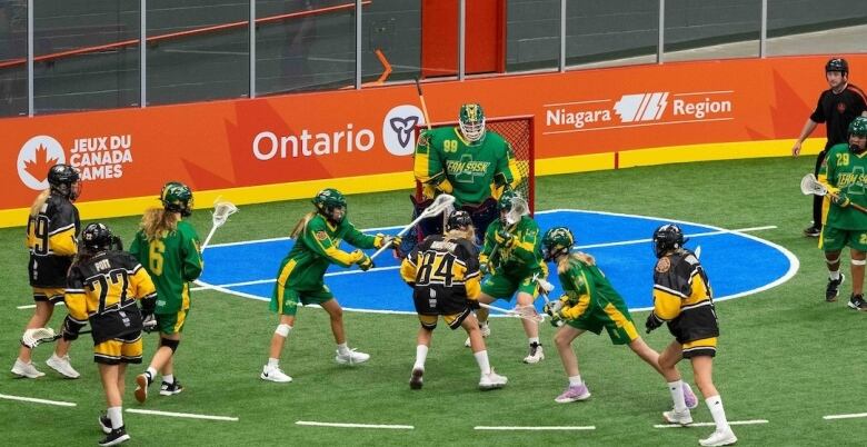 Several female lacrosse players on an indoor field.