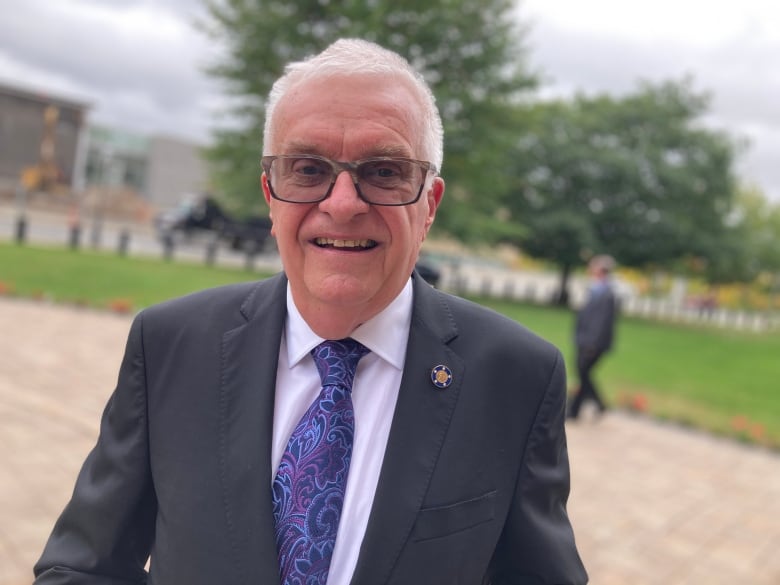 Medium shot of man with white hair smiling at camera