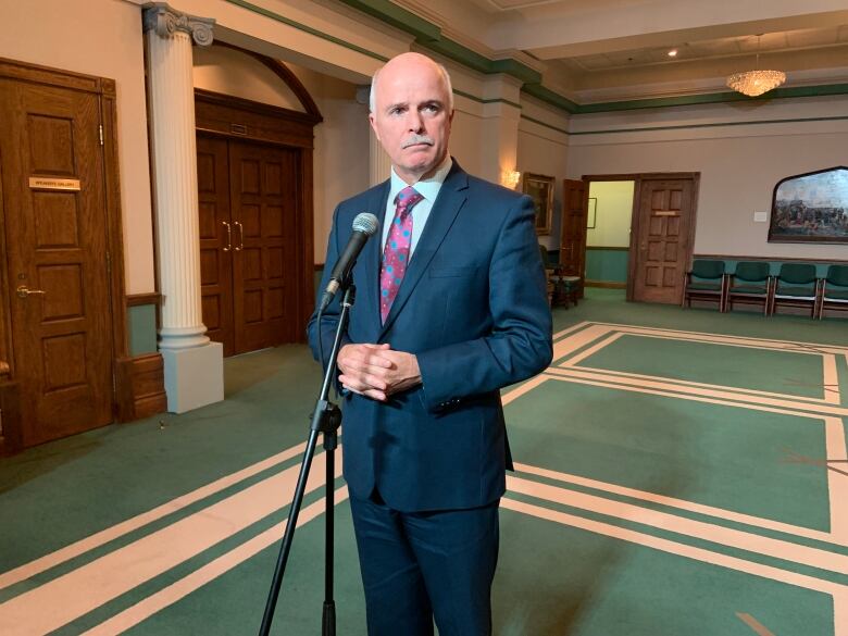 A knees-up shot of a person in a suit standing at a microphone.