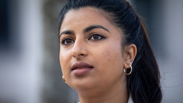 Anjali Appadurai, a brown woman with black hair, looks in the distance.