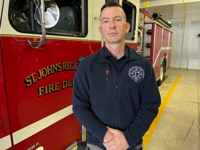 A man standing in front of a fire truck inside a garage. 