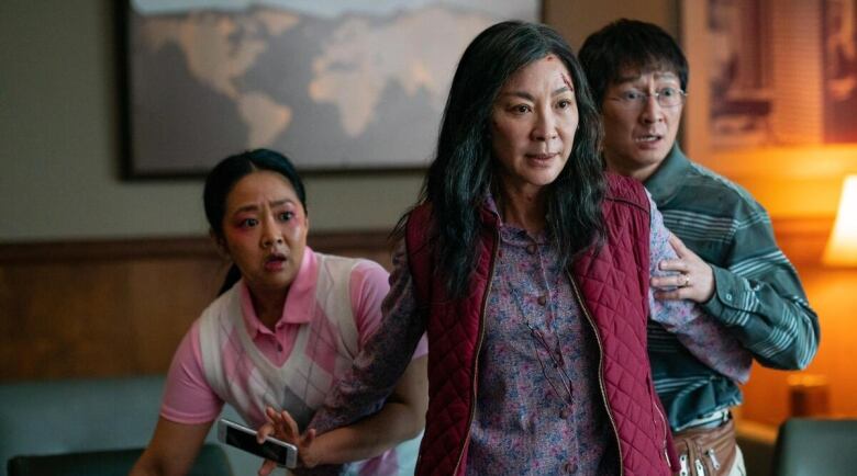 A still frame from the film Everything Everywhere All at Once. Stephanie Hsu, Michelle Yeoh and Ke Huy Quan looking alarmed at something off camera.