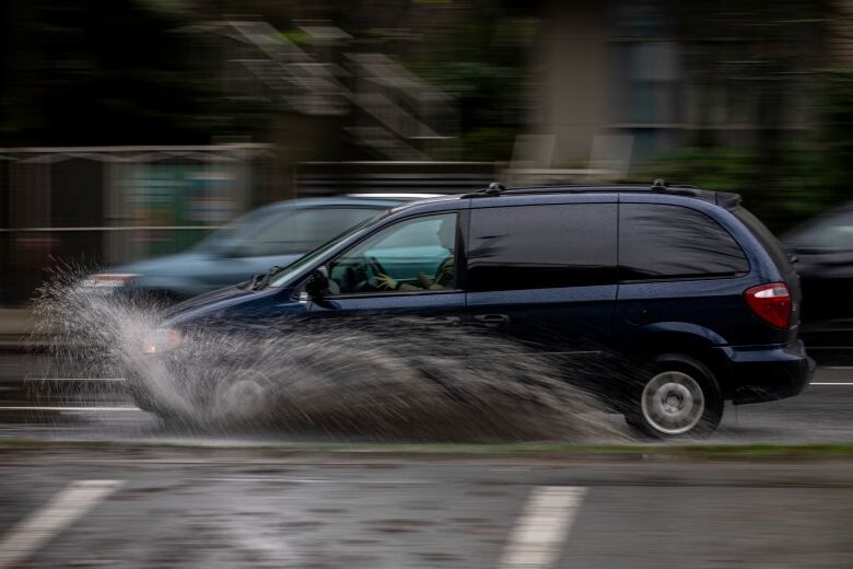 Cars drive through pooling water due to rainfall in Vancouver