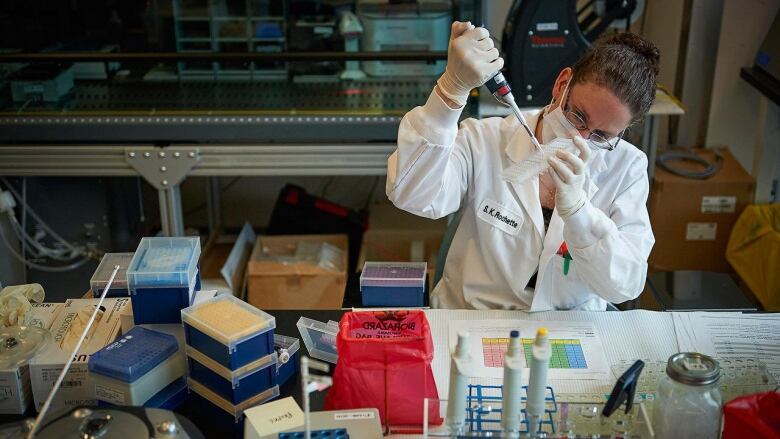 Woman in lab coat using pipette