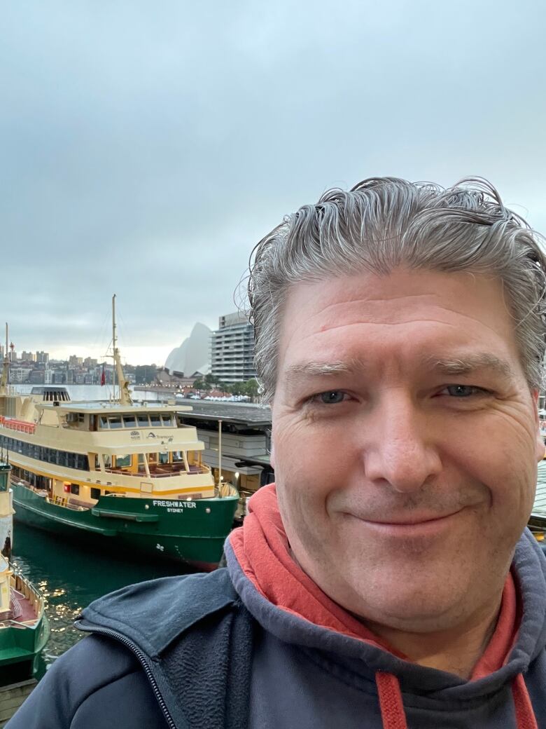 A man snaps a selfie at a harbour in Sydney, Australia