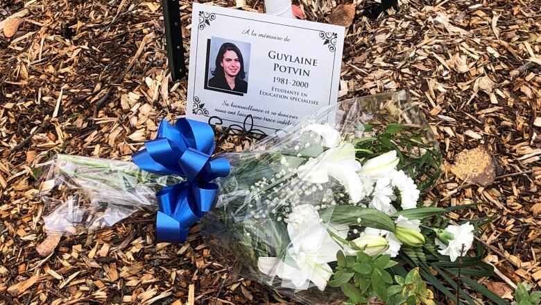 A bouquet of flowers in front of a card that has photo of young woman and a few words.