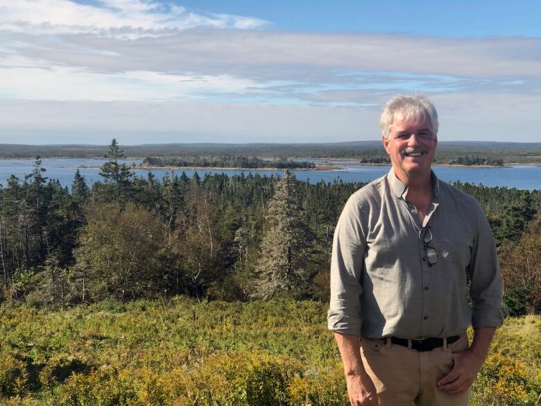 Man stands on top of a hill, overlooking a valley of water