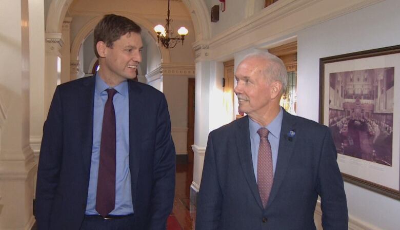 David Eby, a tall white man, smiles at John Horgan, another white man.