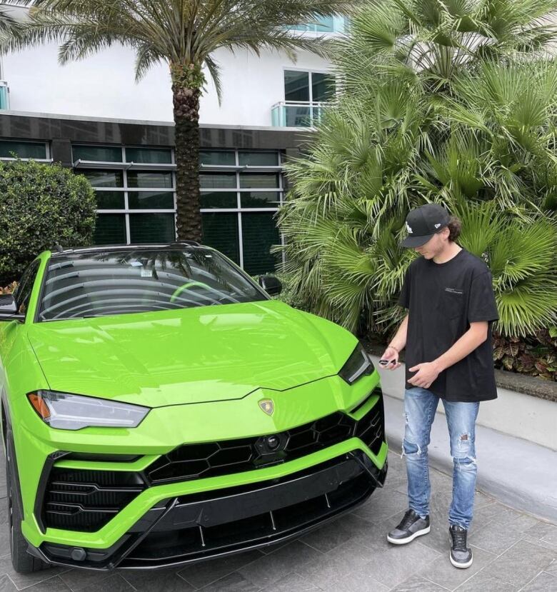 Man standing in driveway with fancy car.