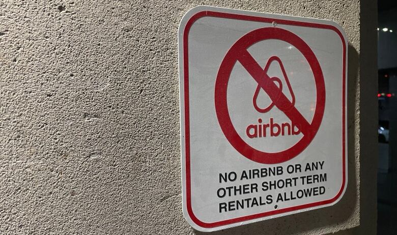 A sign with an AirBNB logo with a slash through it.