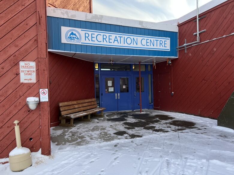 Bright blue doors and a blue sign that says Recreation Centre at the front of a rusty red building.