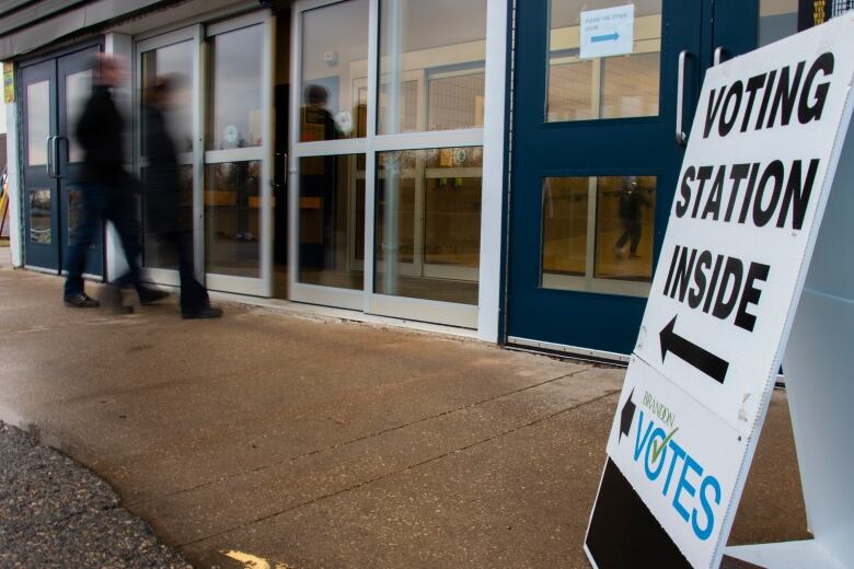 Voters walk by a sign that says 