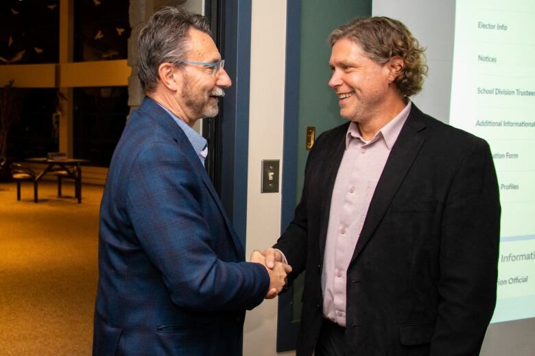 Two men shake hands.