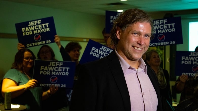 A mayoral candidate smiles as supporters hold 