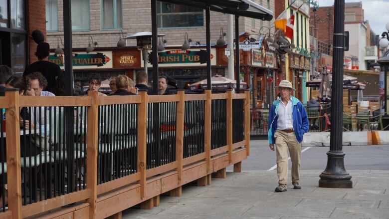 Someone in a light jacket walks past a patio.