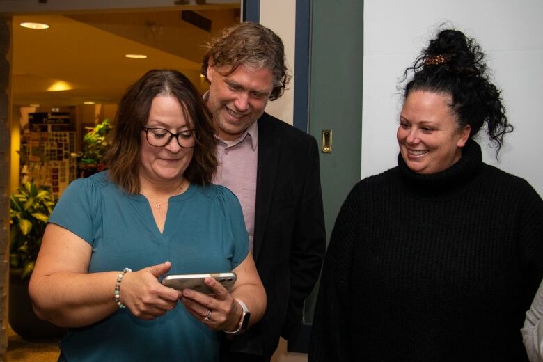 A group of people check out a cell phone.