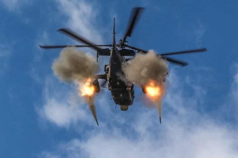 An attack helicopter fires rockets.