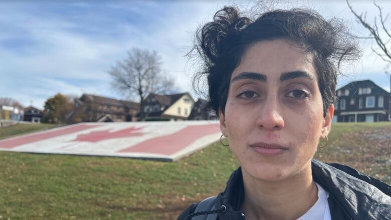 A woman stands in front of a Canada flag that is painted on the ground. 