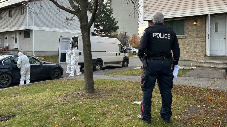 A police officer stands outside a house.