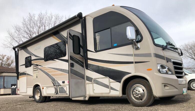 A brown and black RV is parked in an outside lot. 