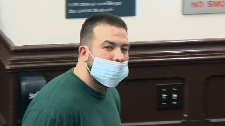 A man wears a medical mask under his nose and looks toward the camera.