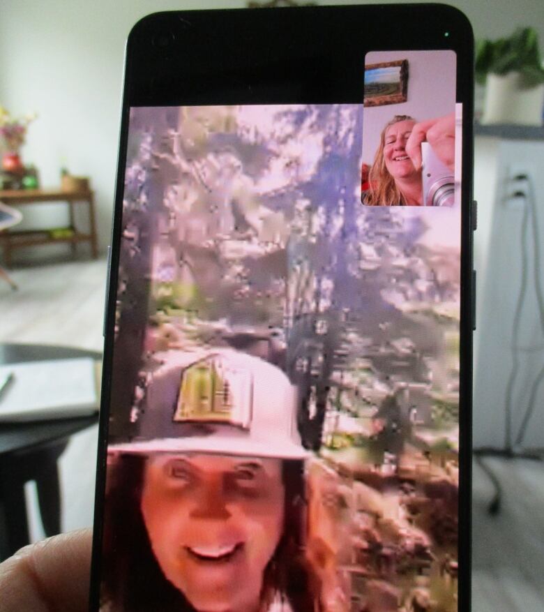 A woman talks with a friend through a video chat on her phone.