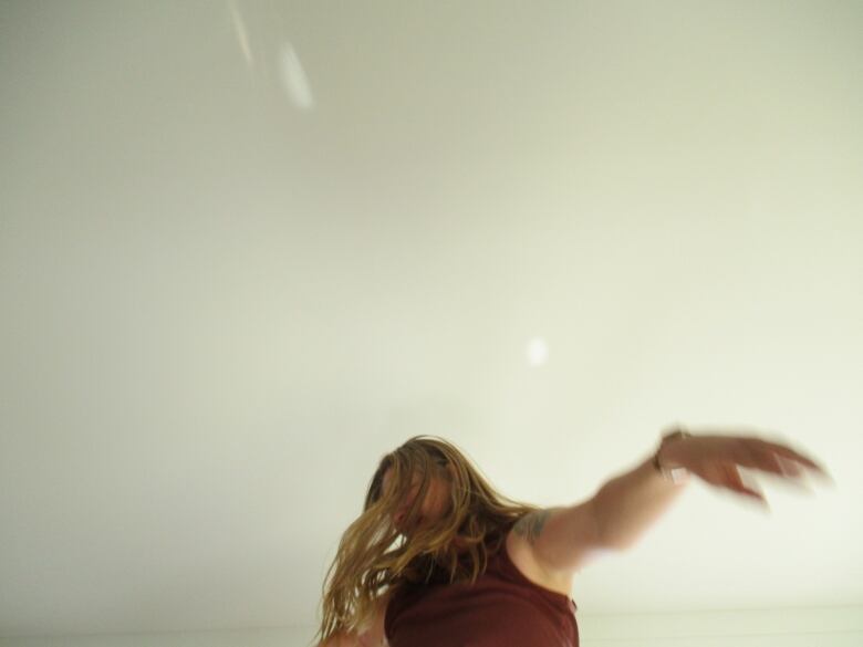 A woman bounces on a small trampoline indoors