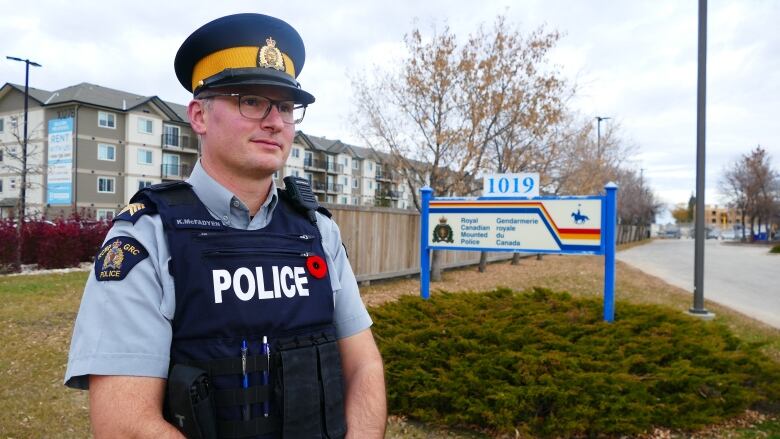 A police officer stands on grass near an RCMP sign.