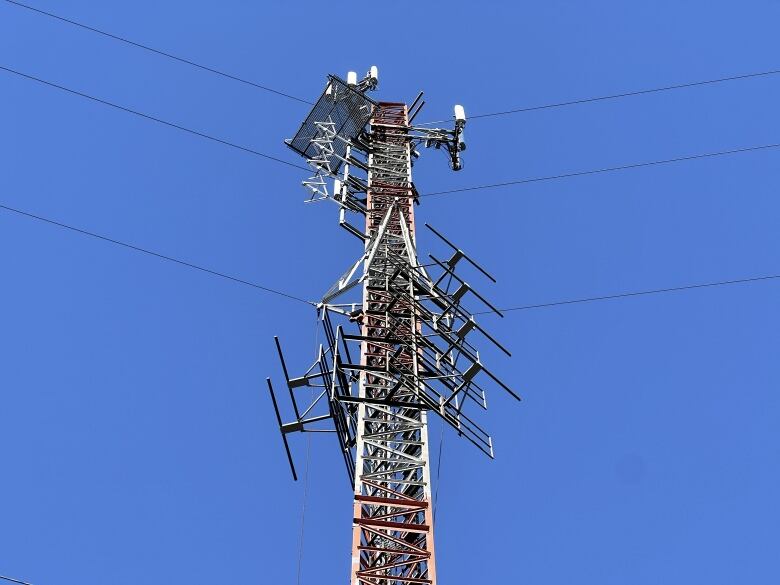 The top of a cell tower is seen in front of a clear blue sky.